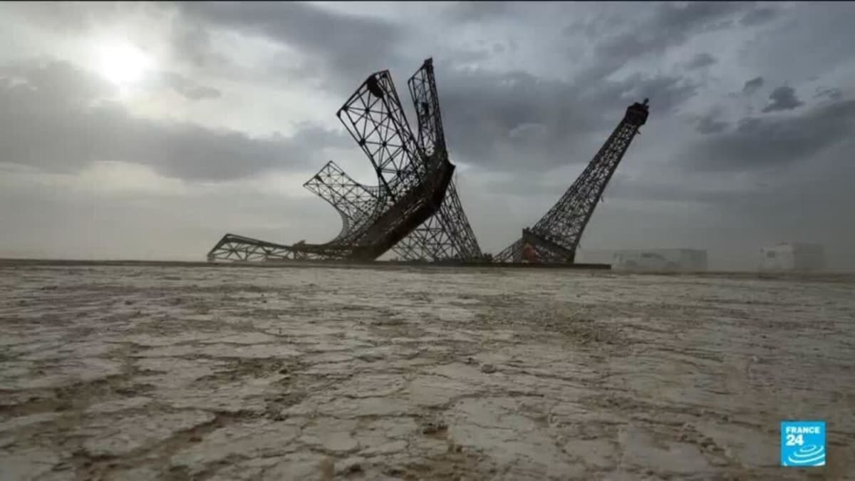 Large broken Eiffel Tower sculpture standing in Nevada desert at Burning Man festival