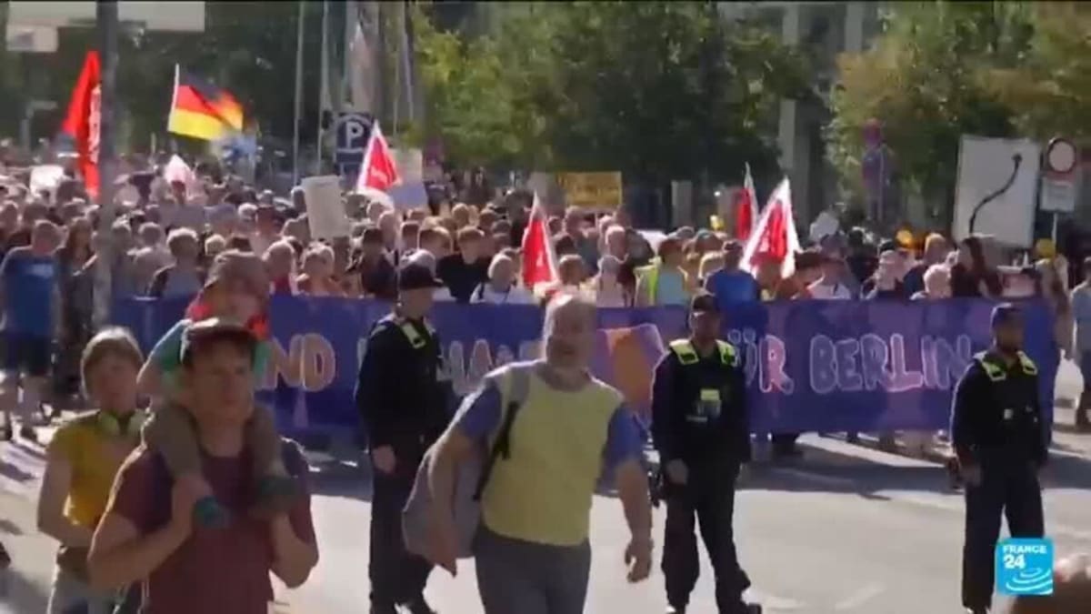 Large crowd of peaceful protesters gathering in German city street holding signs defending democracy