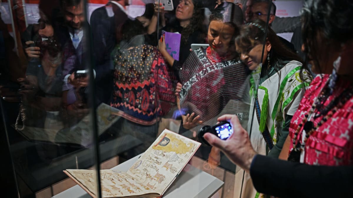 Colorful 16th-century Aztec manuscript with vibrant pictograms displayed in glass case at museum