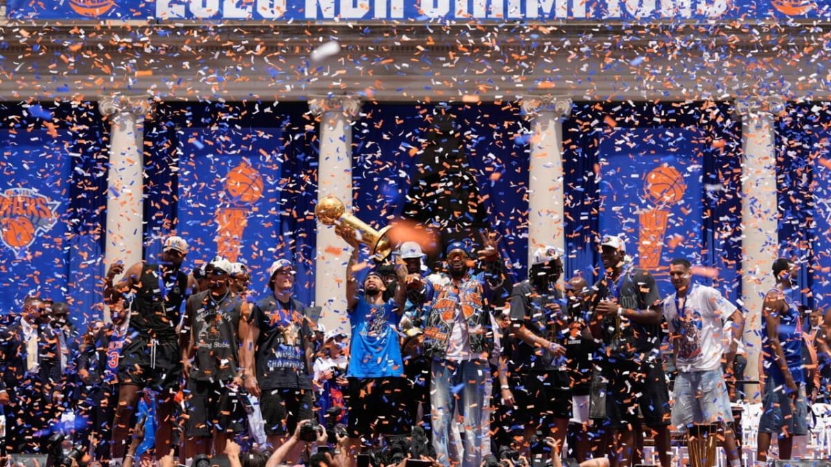 New York Knicks players celebrating with championship trophy during Manhattan victory parade surrounded by confetti