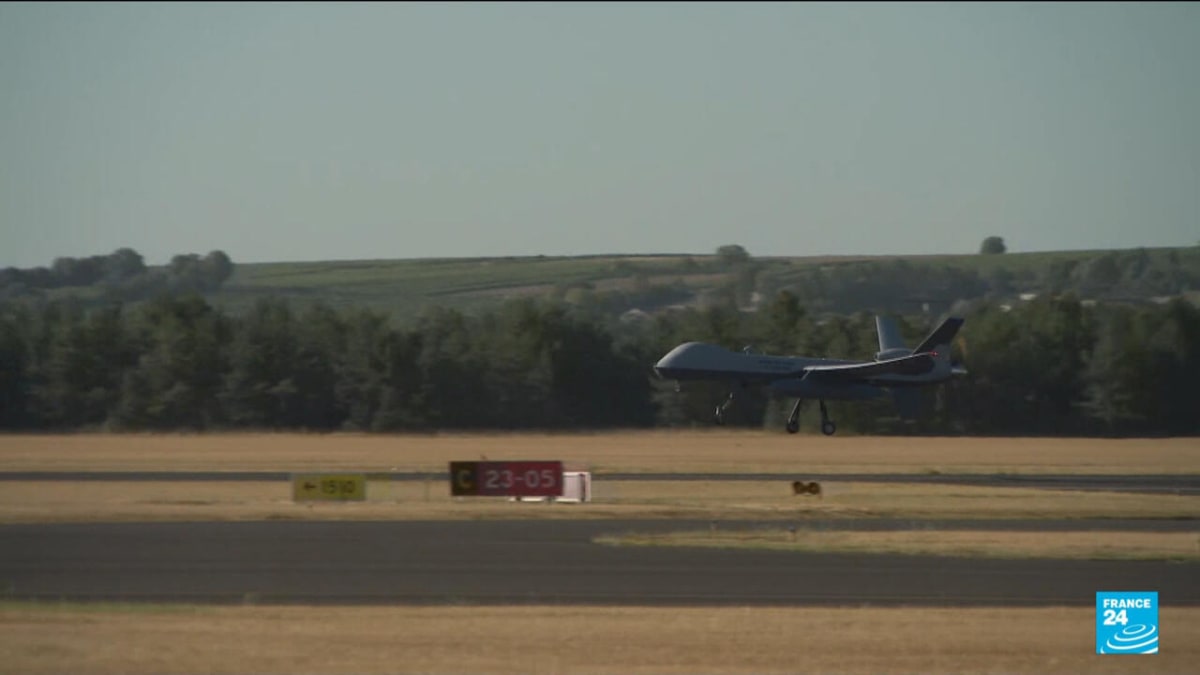 French military drone flying over smoky forest while soldiers operate equipment below