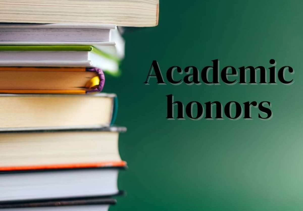 Young female college student studying at desk with books and laptop computer