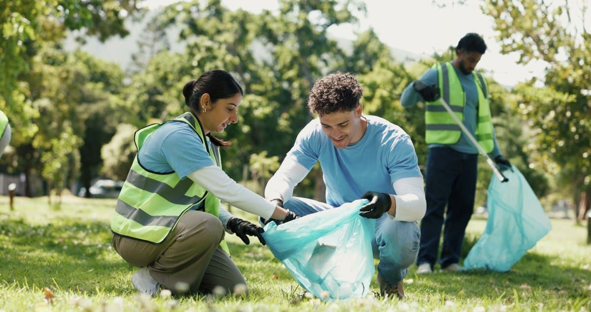 Volunteers in gloves picking up litter along roadside during community Earth Day cleanup event