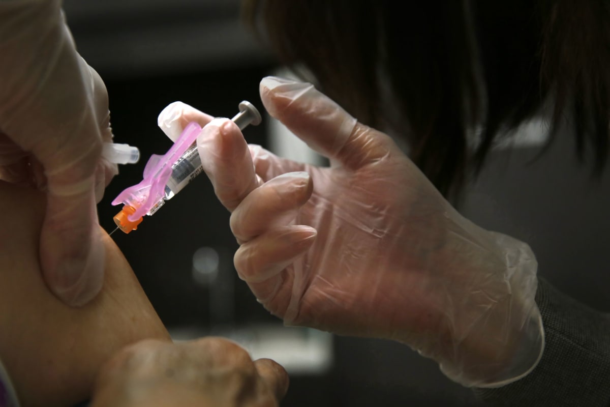 Elderly adult receiving flu vaccine injection from healthcare provider in medical office