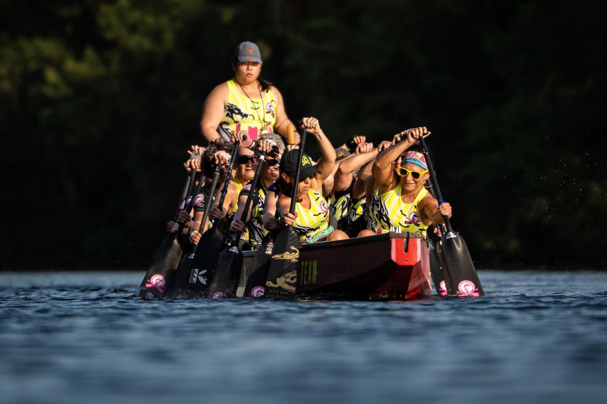 Breast cancer survivors paddle dragon boat in sync on Lady Bird Lake in Austin