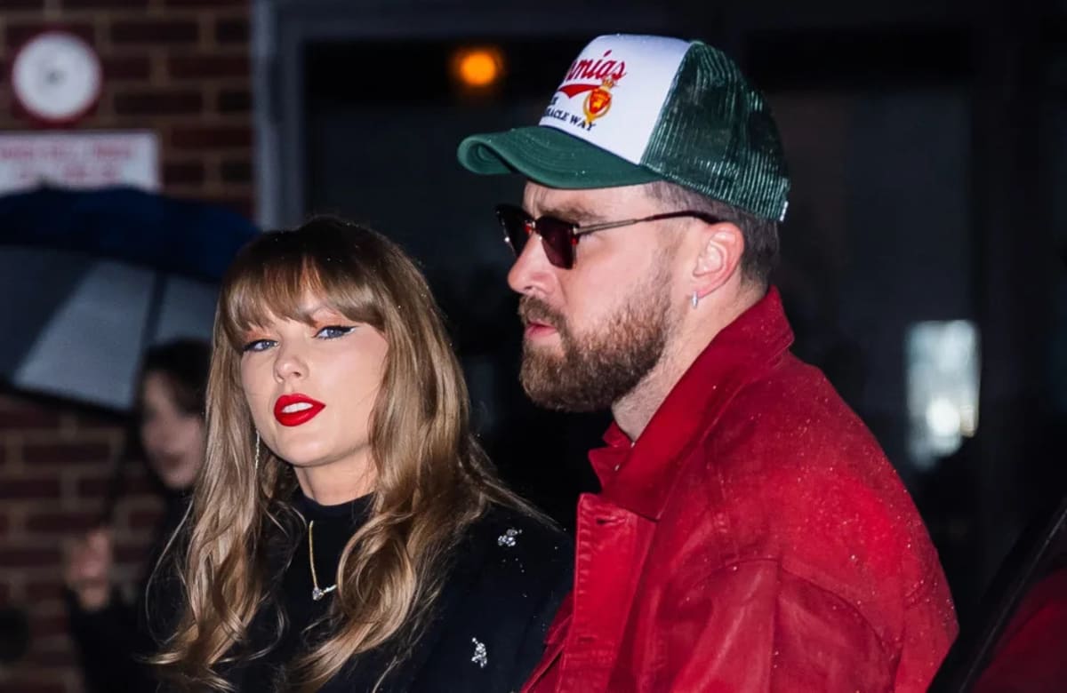 Taylor Swift performing on stage with heart hands gesture toward audience members