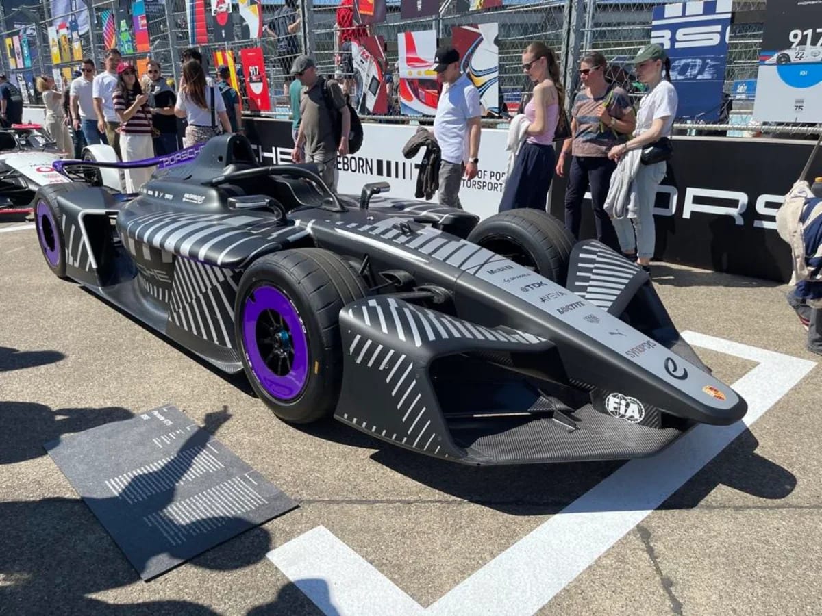 Formula E race car with blue and silver technology components displayed alongside racing vehicle