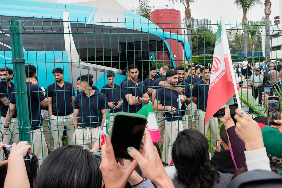 Iranian soccer players departing from Tijuana hotel surrounded by supportive fans waving goodbye