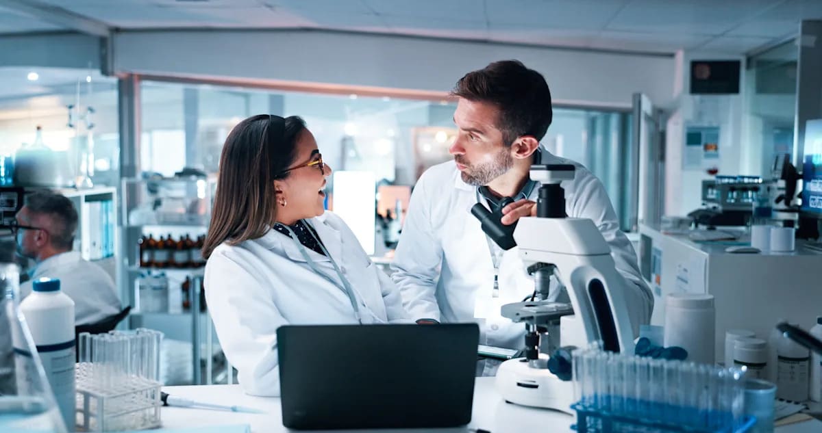 Scientists working in modern laboratory with computer displays showing AI-assisted research workflows