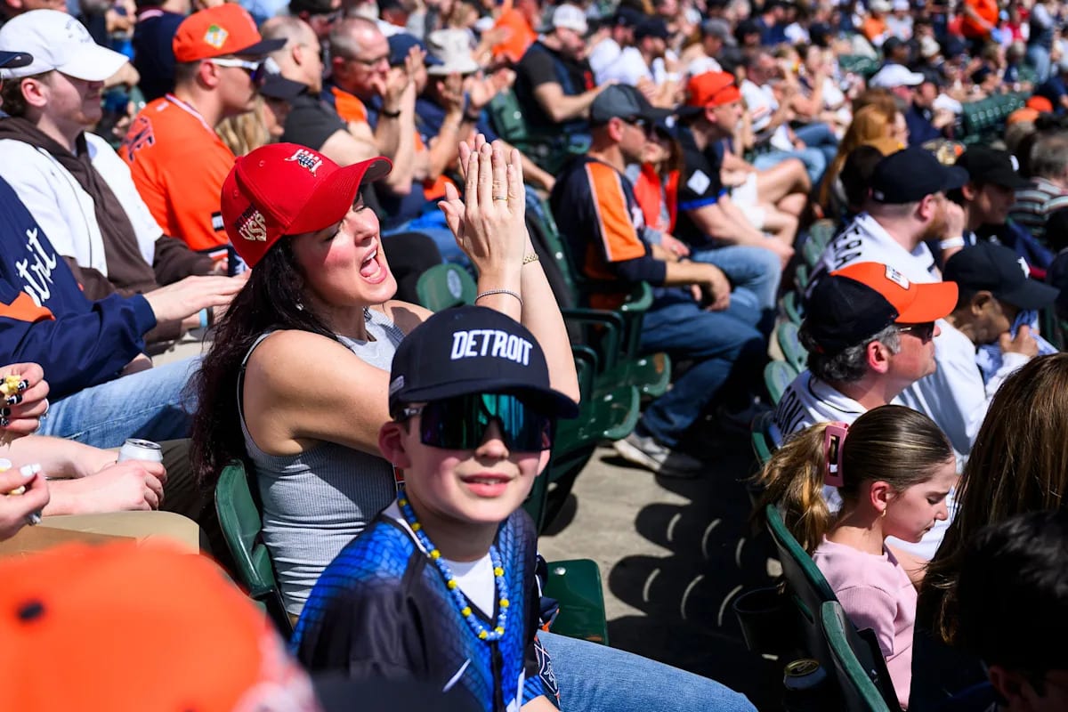 Excited Detroit Tigers fans wearing Old English D caps celebrate at packed Comerica Park stadium