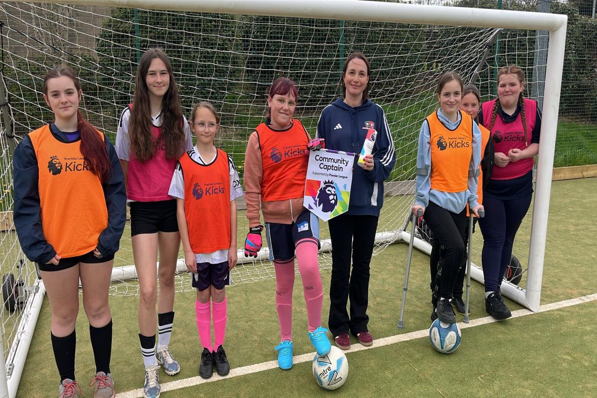 Laura Evans smiling with diverse group of young footballers at Exeter training session