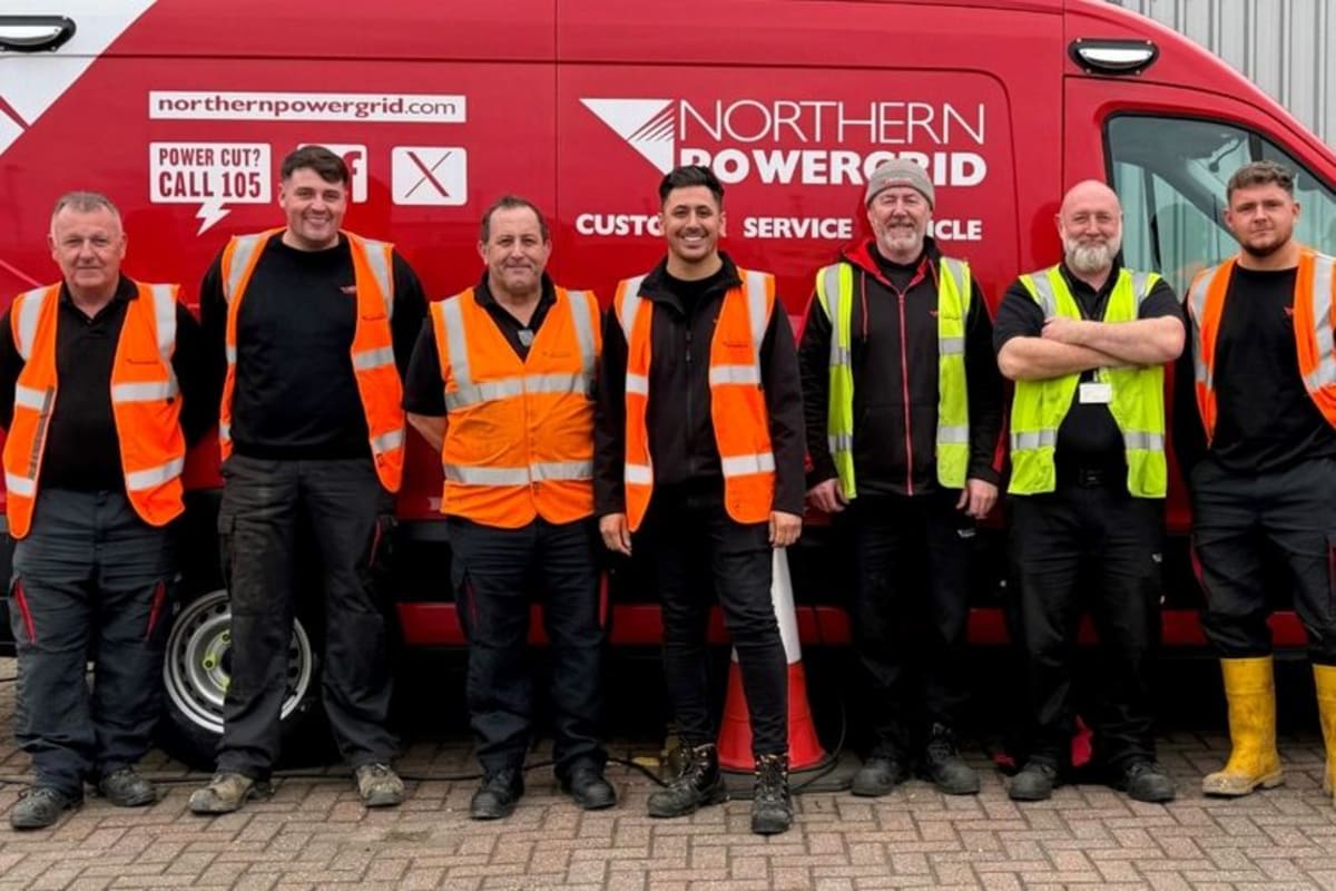 Northern Powergrid engineers in safety gear present oversized check to charity representatives