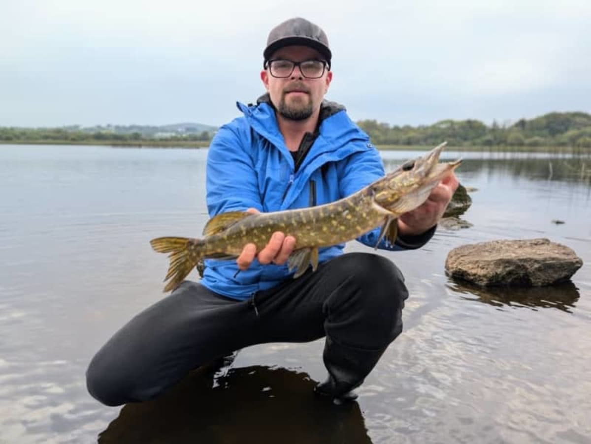 Researcher holding freshwater fish in clear stream water for conservation study