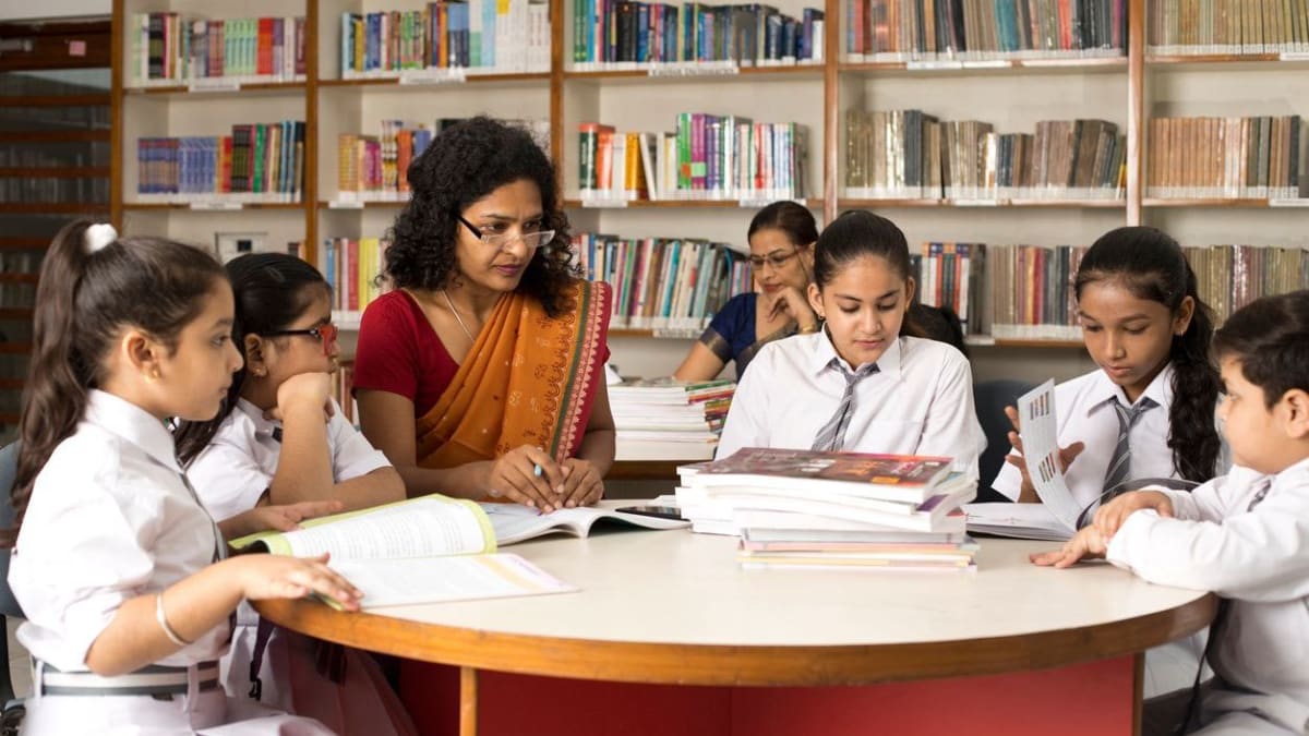 Teacher engaging warmly with students in bright school library setting showing supportive learning environment