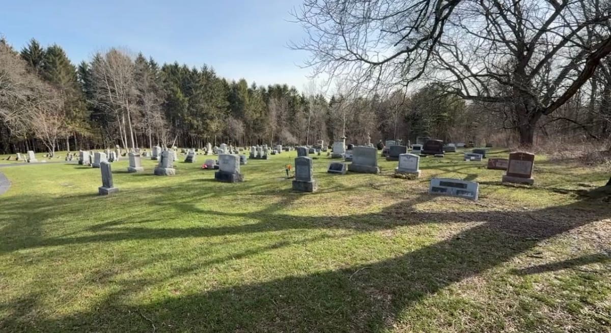 Volunteers cleaning weathered historic gravestones at cemetery with cleaning supplies and tools
