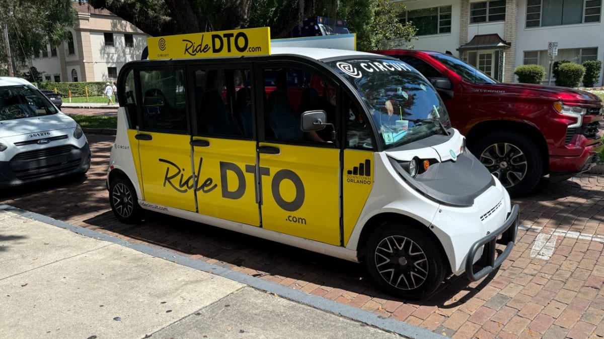Electric ride-share vehicle driving through downtown Orlando streets serving local residents