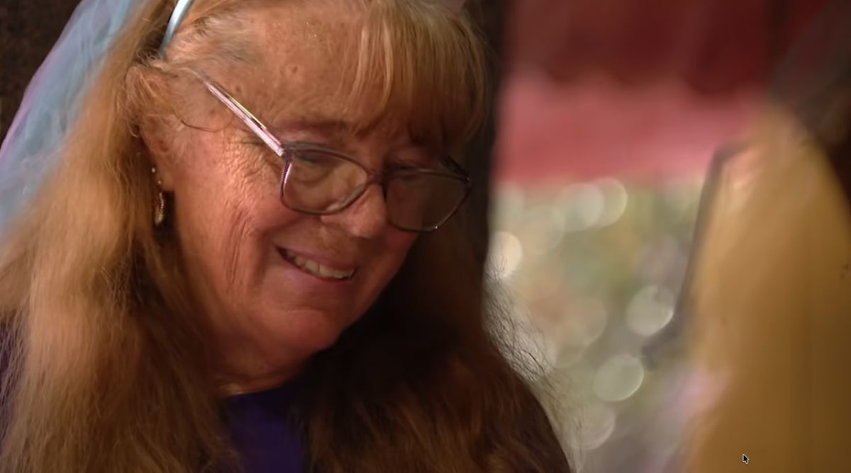 Grandmother Donna Miller smiling at Give Kids the World carousel with families in background