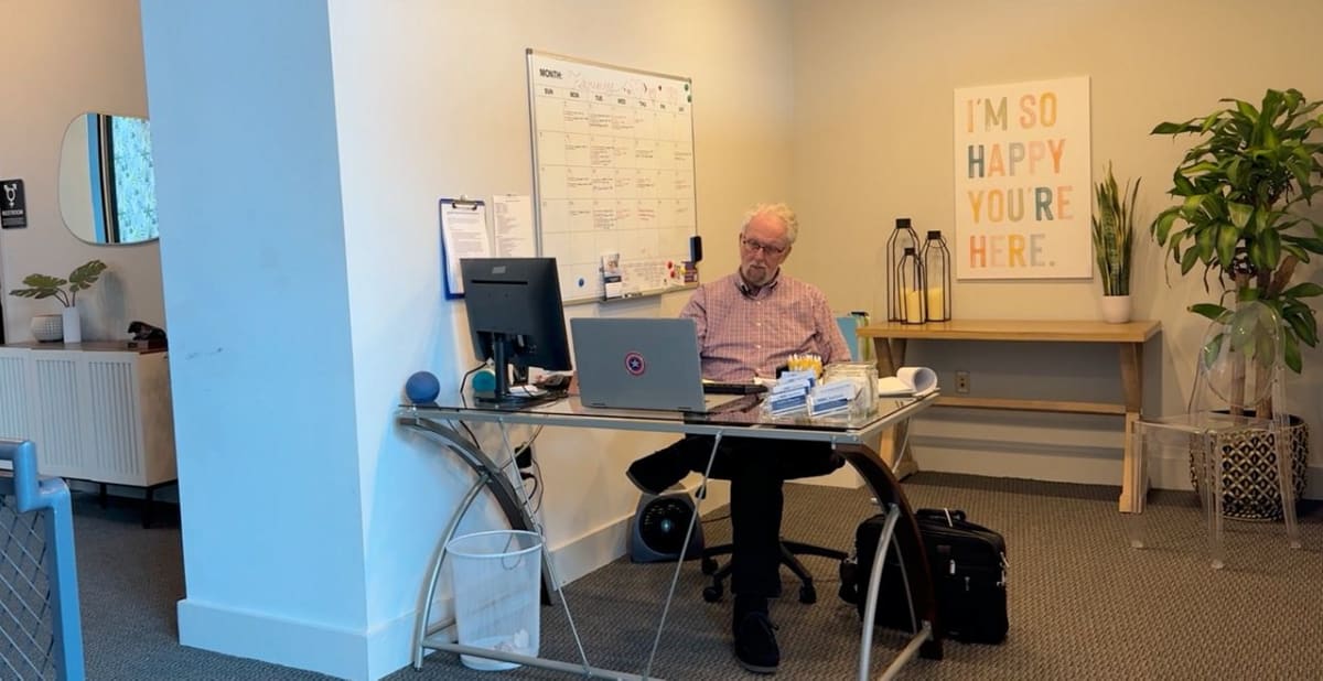 Jim Love smiling while volunteering at NAMI Charlotte mental health helpline desk