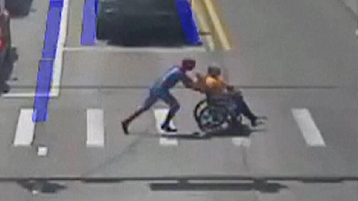 ** Street security camera footage shows man in Spider-Man costume pushing wheelchair across intersection
