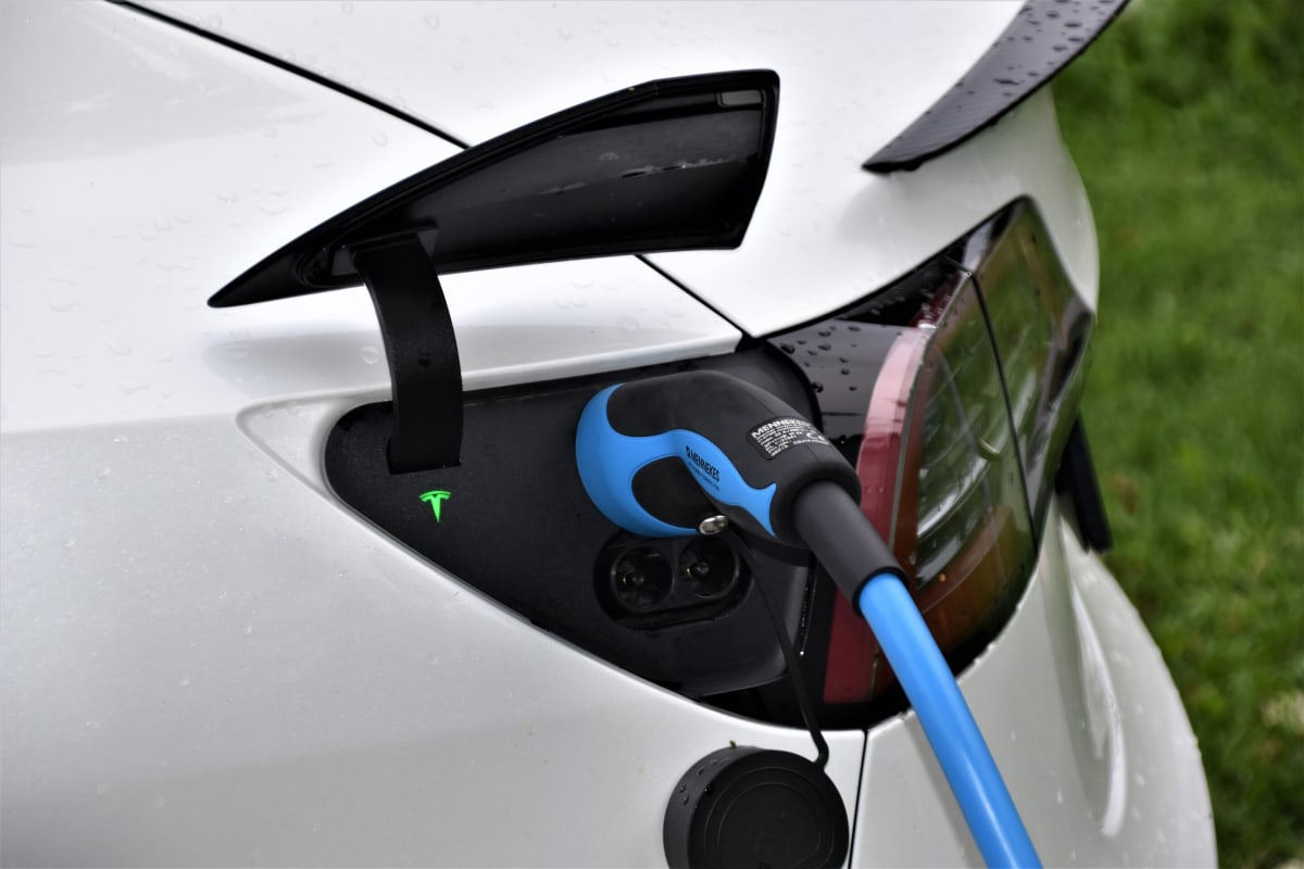 Electric vehicle plugged into charging station at home driveway during evening
