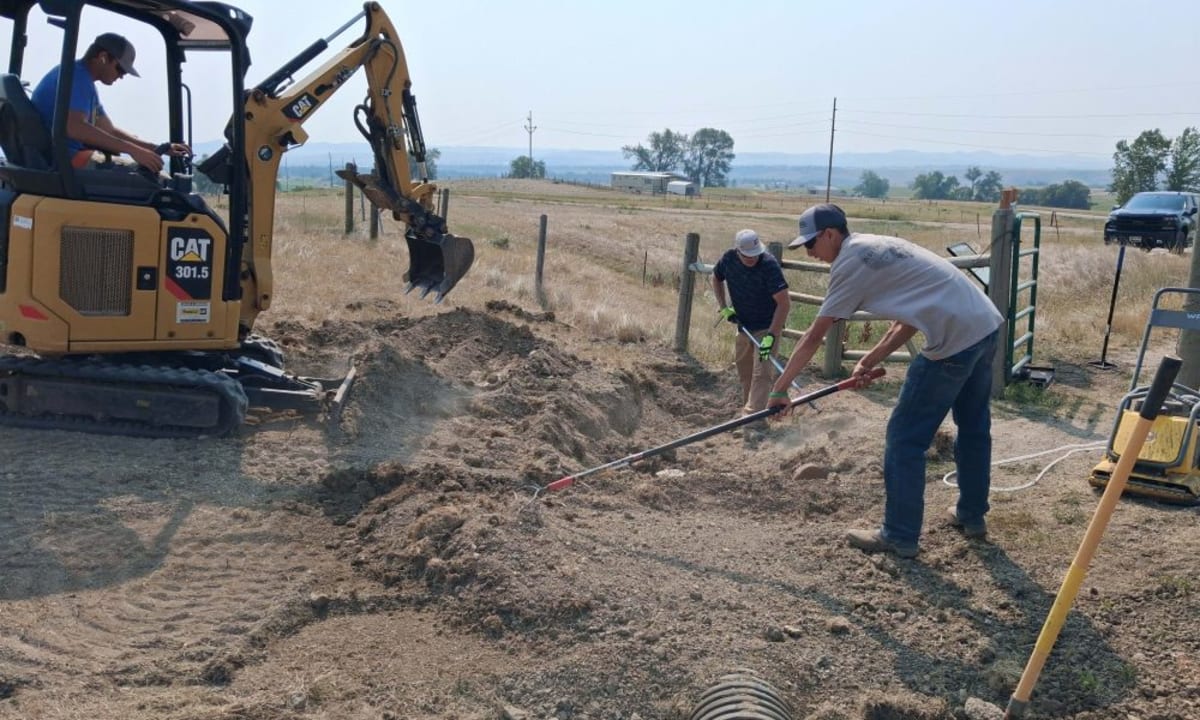 Volunteers working together with tools to build a winding mountain trail through natural terrain