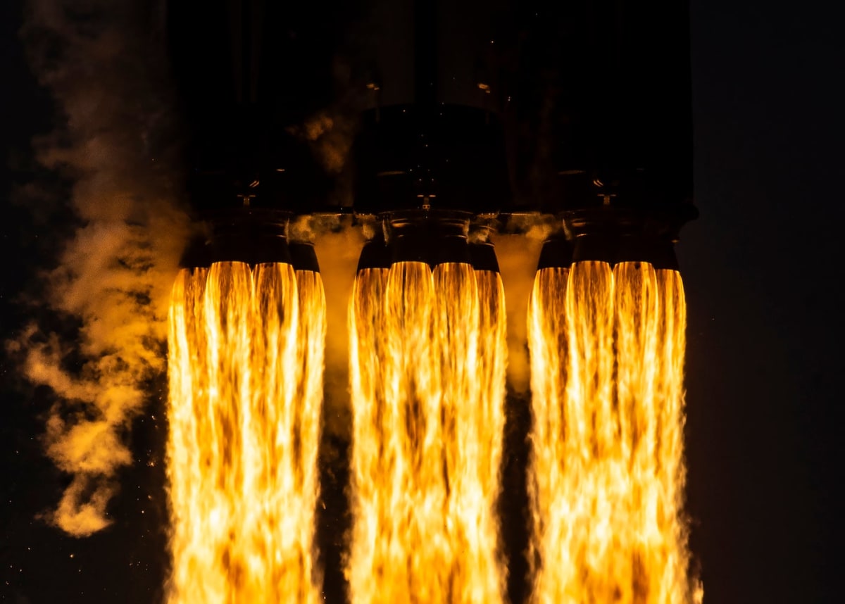 SpaceX Falcon Heavy rocket launching into blue sky with white exhaust plume