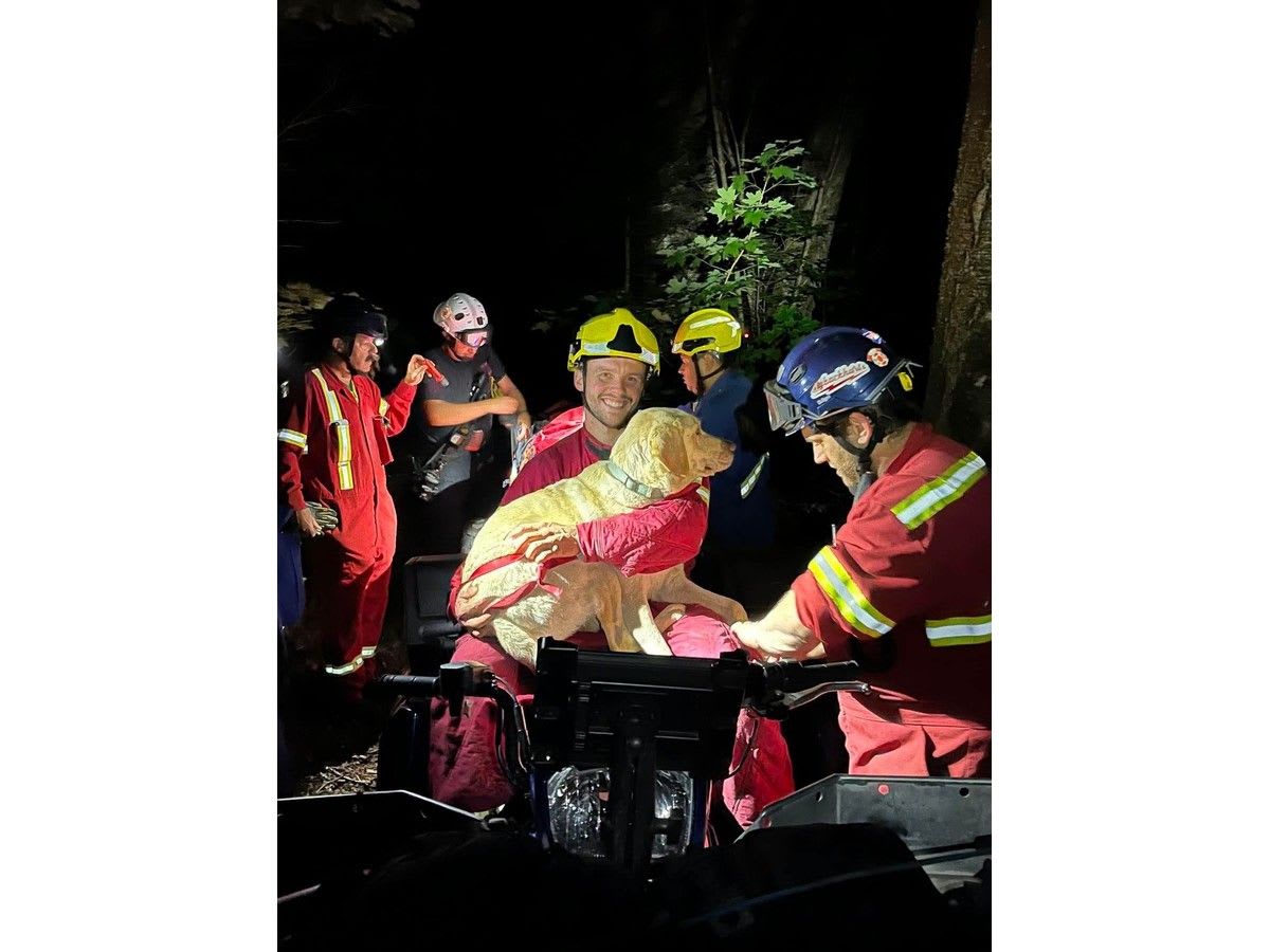 Firefighter Ian Doucette holds Reese the yellow lab after cliff rescue at Blomidon Provincial Park
