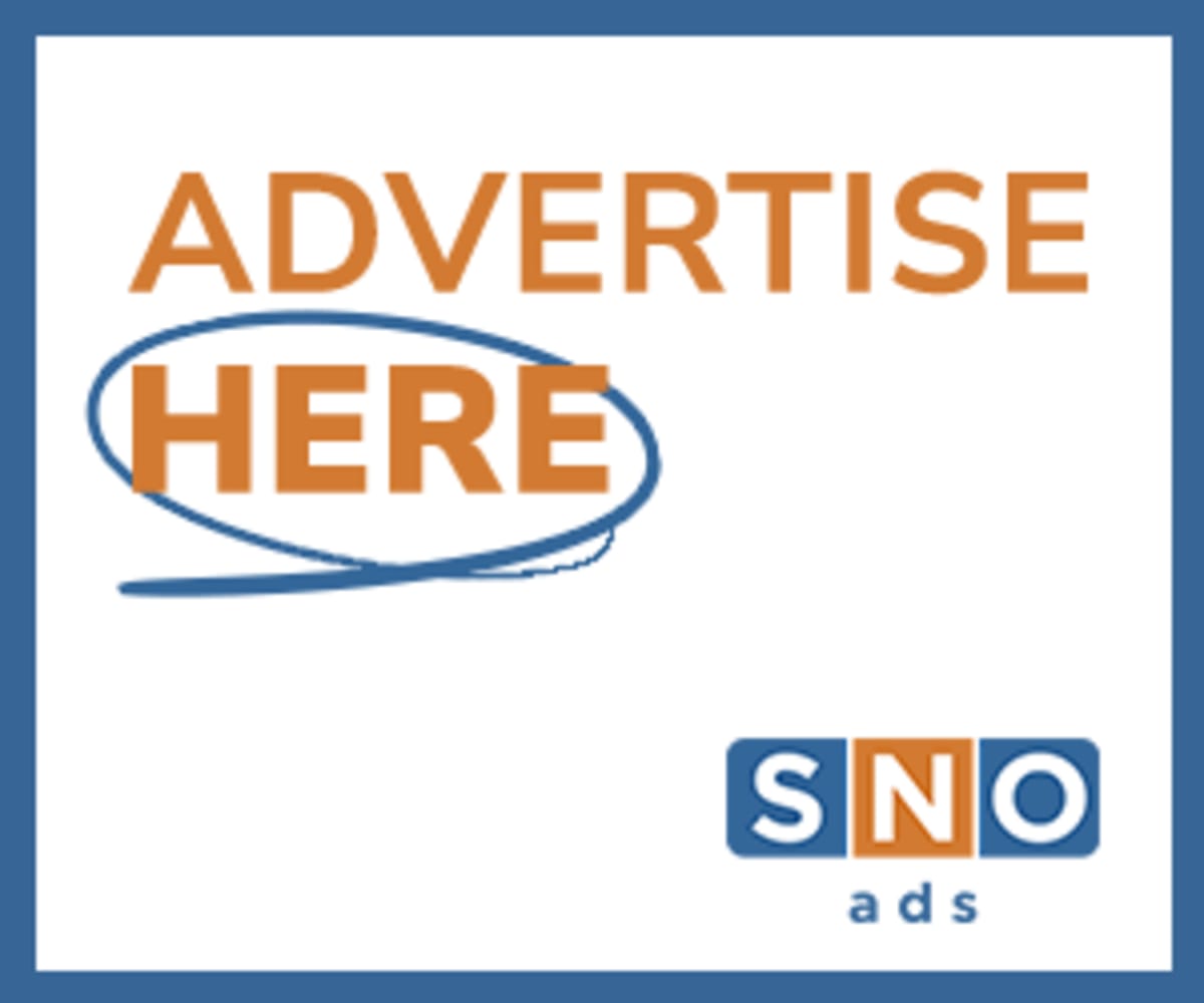 College student Anna Ince smiling at radio broadcasting equipment in studio