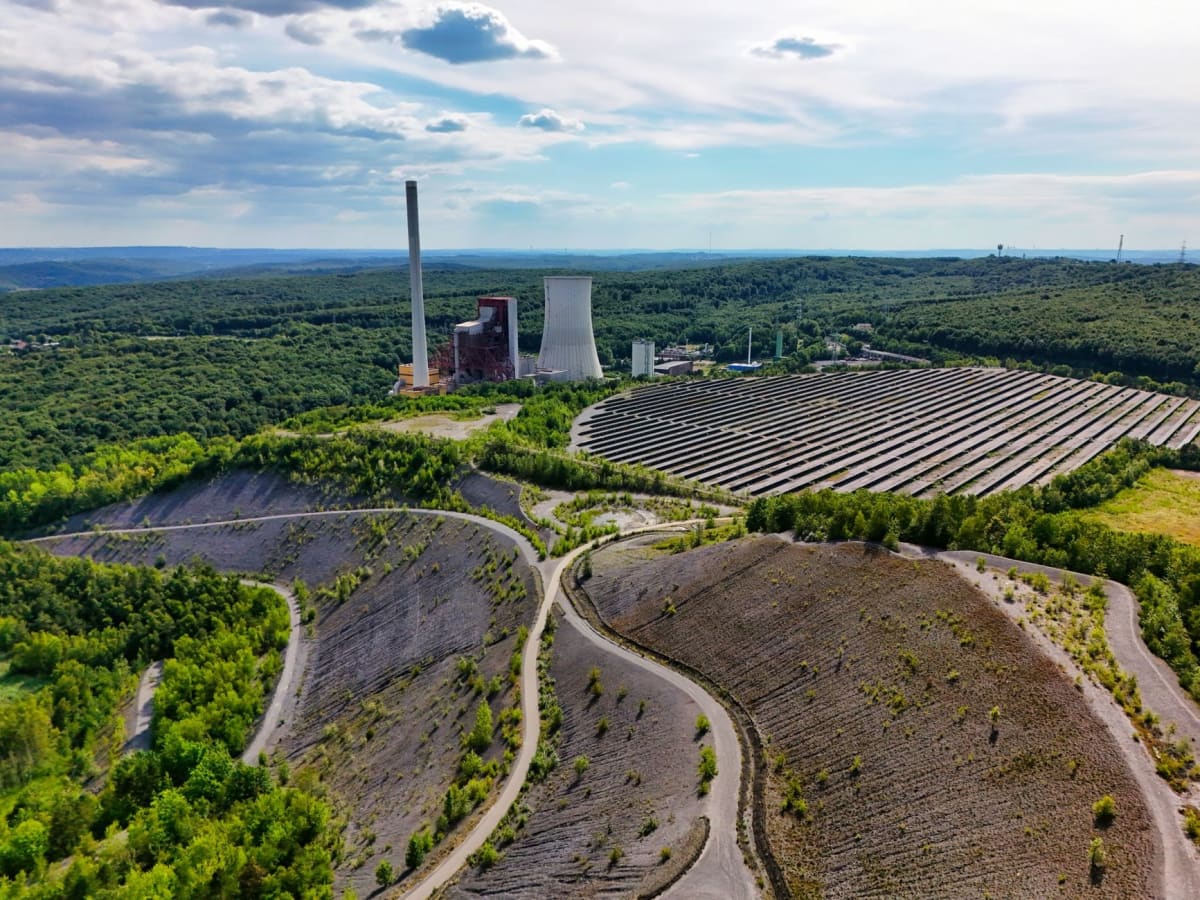 Large solar panel array stretching across open landscape with modern data center building in background