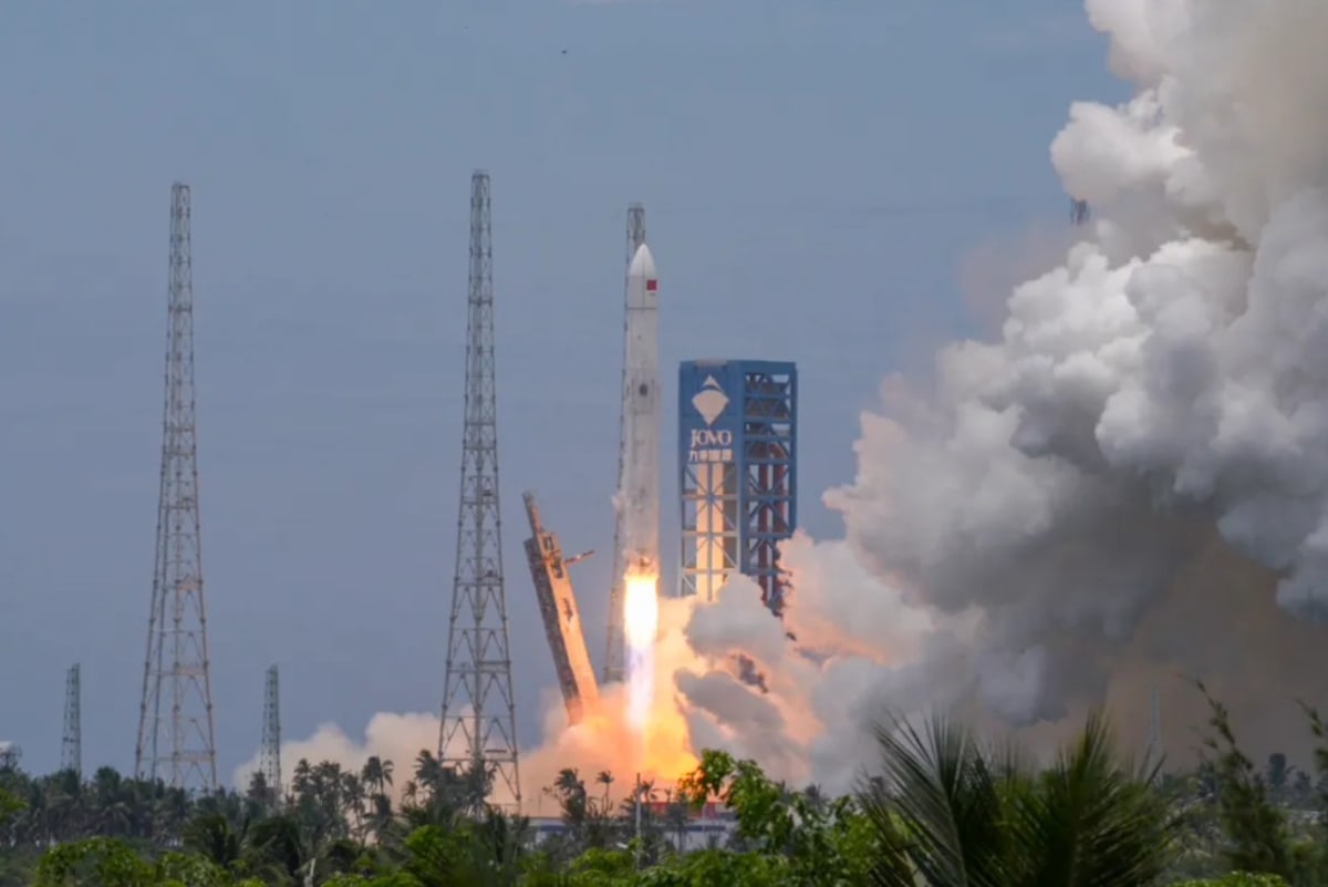Long March 10B rocket booster descending with engines firing into recovery net on Chinese ship
