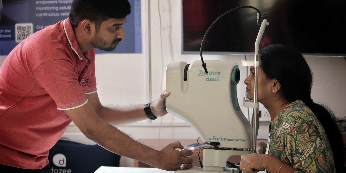 Indian engineer Abhishek Appaji demonstrating the Smart Eye Kiosk retinal scanning device on patient