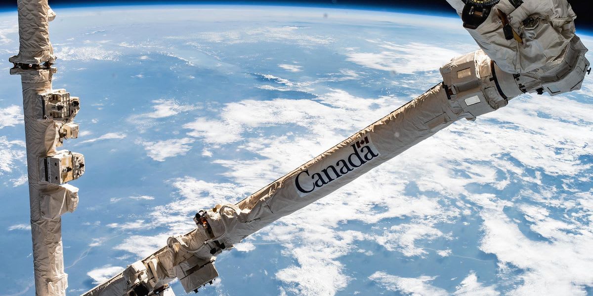 Canadarm robotic arm extended from space shuttle with Earth visible in background