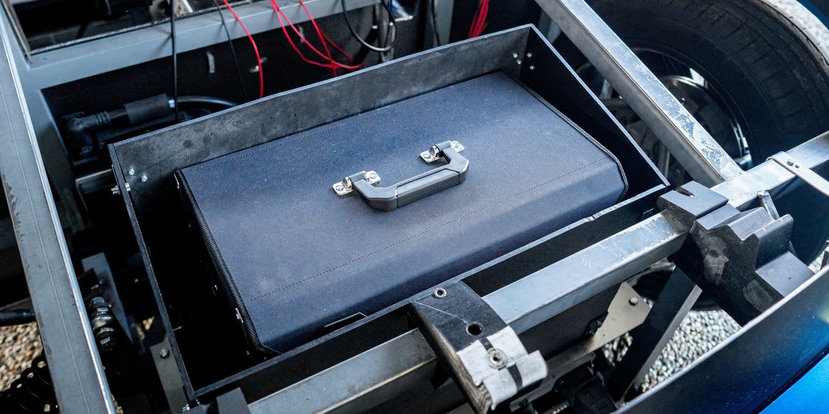 Students standing beside white Aria electric vehicle prototype at Eindhoven University