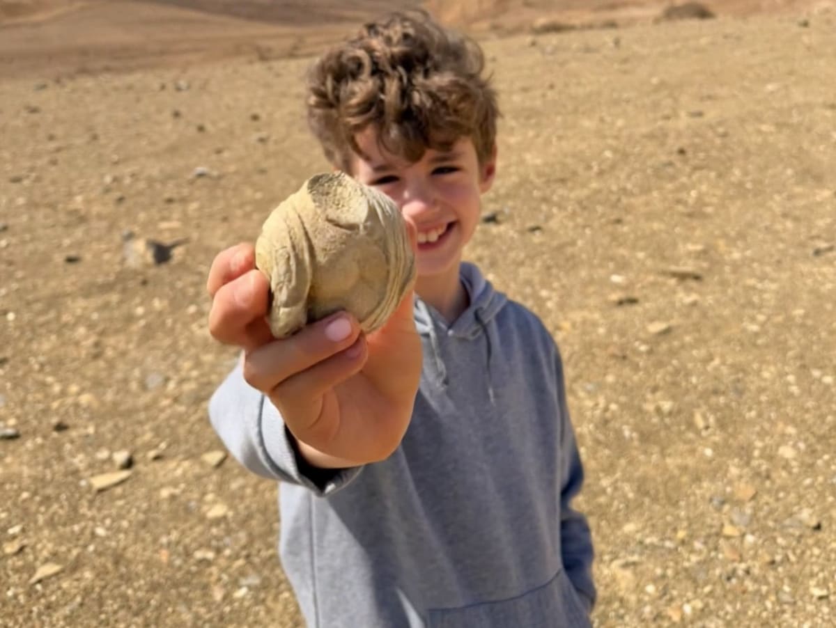 Eight-year-old boy holding small ancient Roman stone statuette fragment showing carved torso