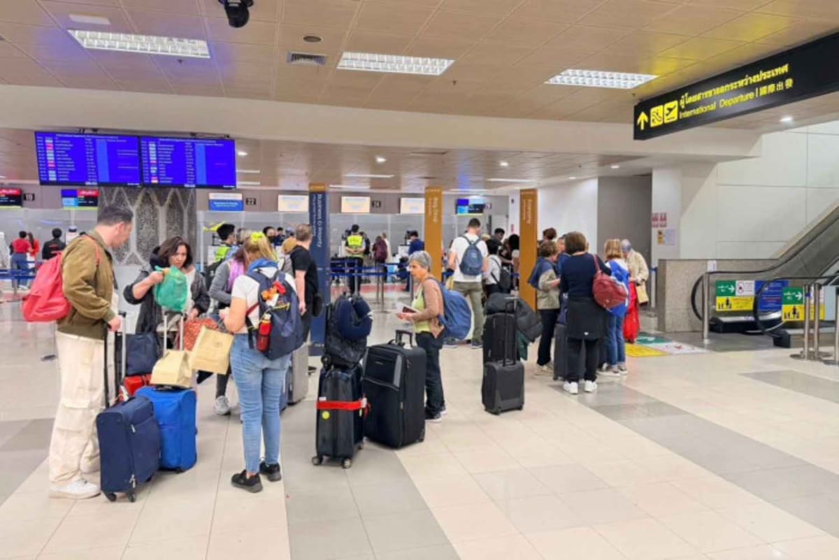 Travelers walking through busy Suvarnabhumi International Airport terminal in Bangkok, Thailand