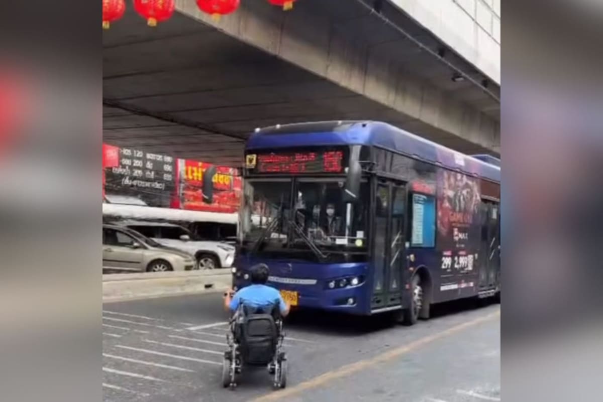 Wheelchair user positioned in front of bus on Bangkok street demanding right to board public transportation