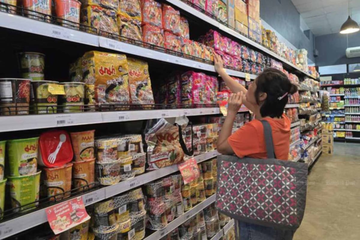 Shopper browsing instant noodle products on supermarket shelves in Bangkok, Thailand