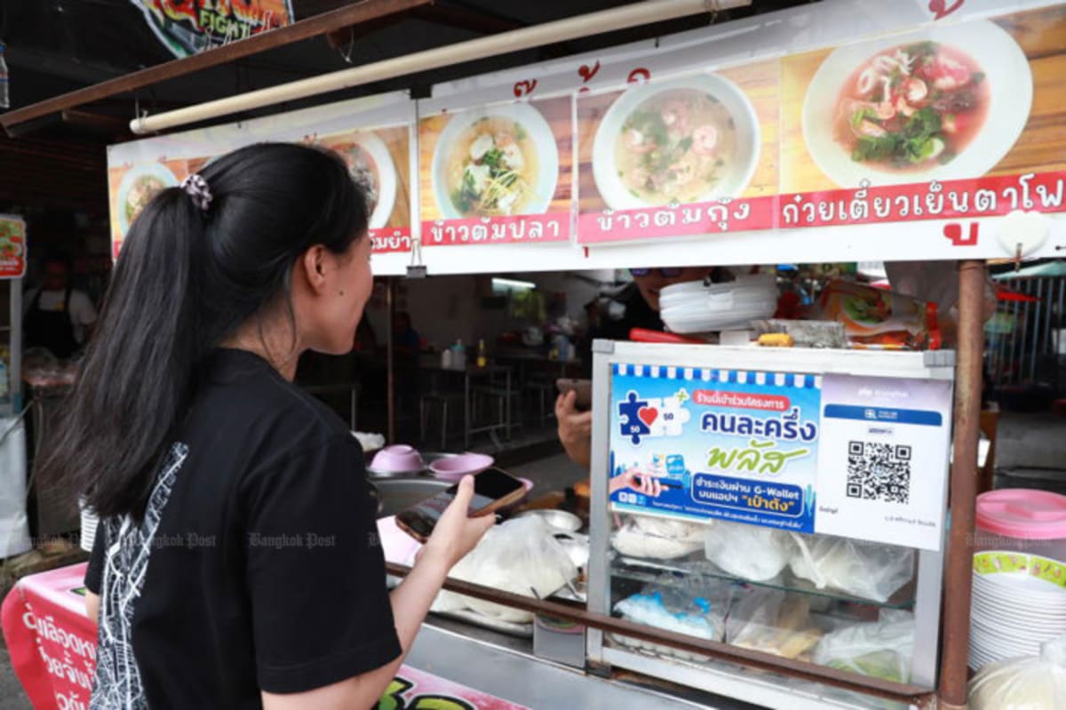 Woman uses mobile payment app at Thai market food vendor stall