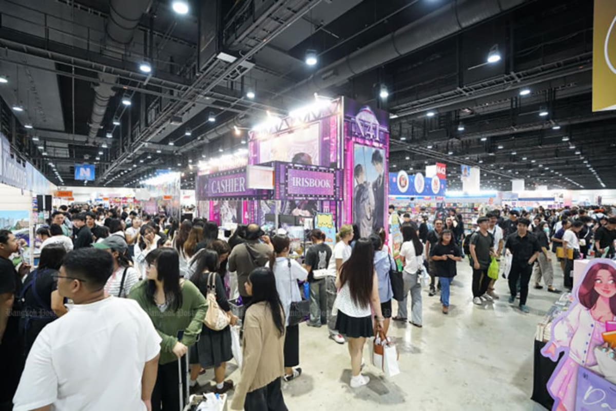 Crowds of young people browsing books at colorful displays in Bangkok book fair convention hall