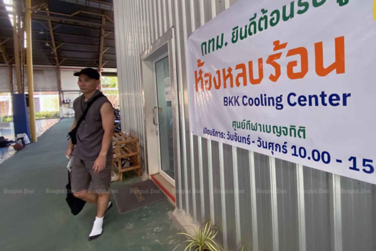 Person exiting air-conditioned cooling center building in Bangkok during extreme heat conditions