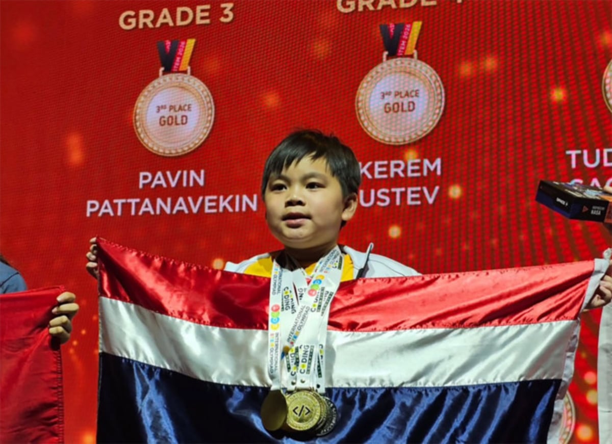 Nine-year-old Pavin Pattanavekin holding Thai flag on stage after winning coding championships in Rome