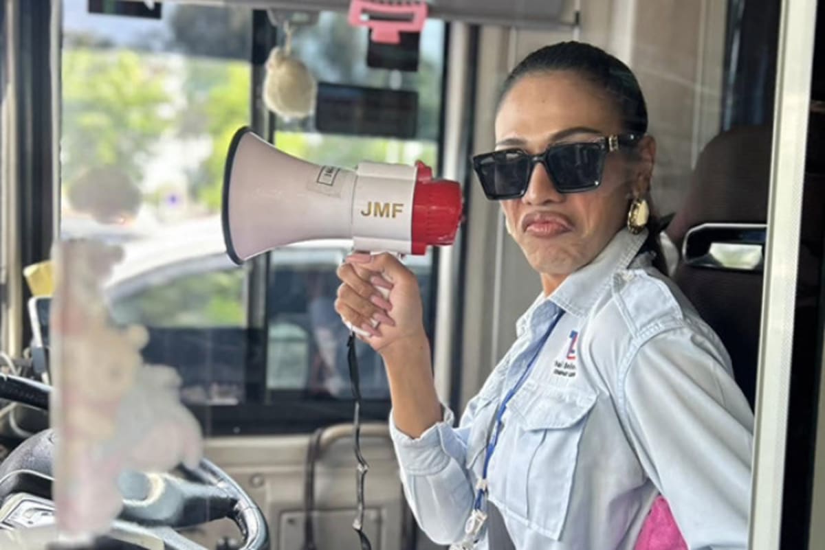 Bangkok bus captain Gigi holding megaphone while standing near her public transit bus