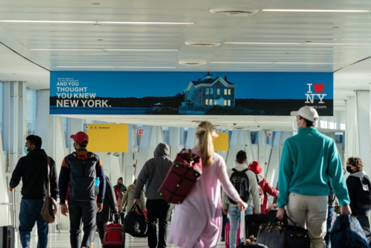 Travelers walking through bright airport terminal with luggage, representing reunited families