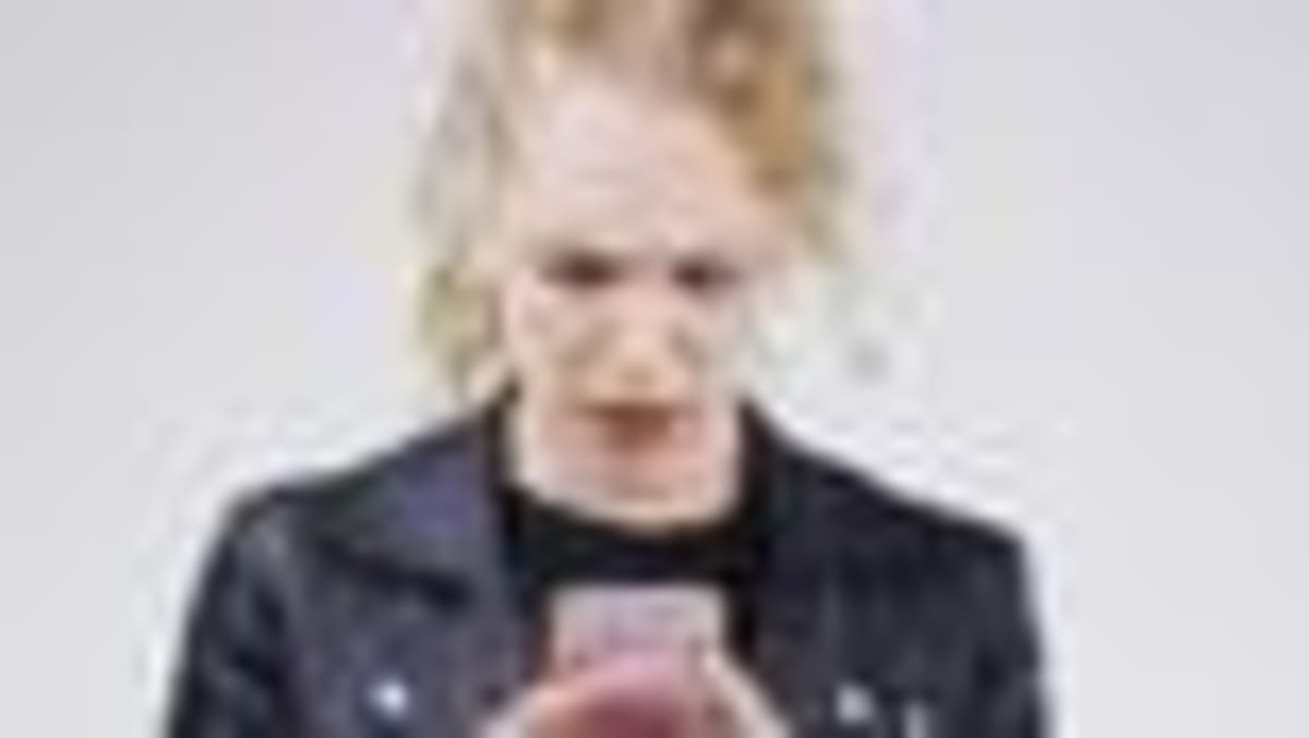 Person reading physical book in quiet library with natural lighting and wooden shelves