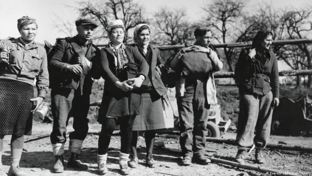 ** Black and white historical photograph showing civilians during World War II forced labor period