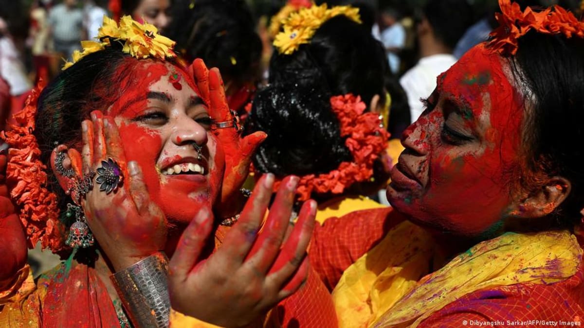 ** Joyful crowds covered in vibrant colored powder celebrate Holi festival in India's streets