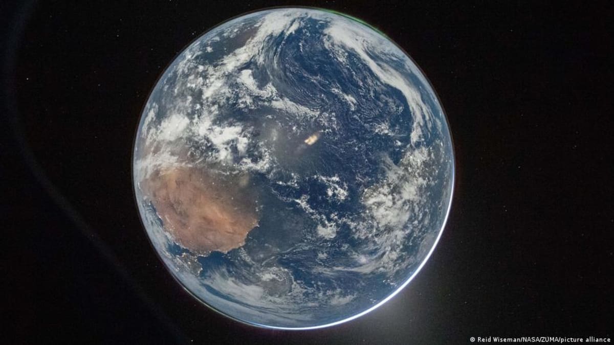 Curved Earth with swirling cloud patterns over blue oceans photographed from Orion spacecraft window