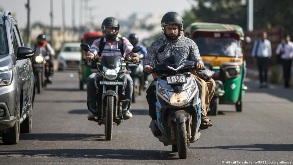 ** Motorcycles and scooters on a busy Delhi street surrounded by thick smog and pollution