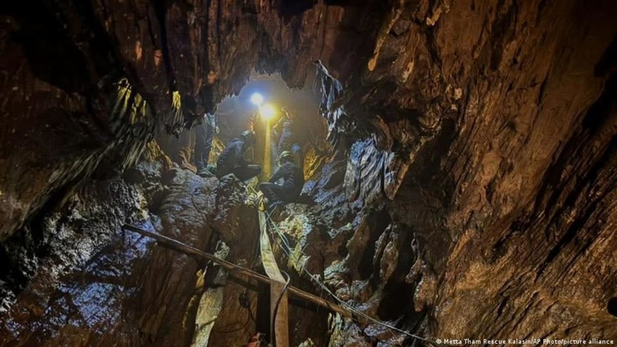Exhausted rescued villager being assisted by two rescue workers outside flooded Laos cave