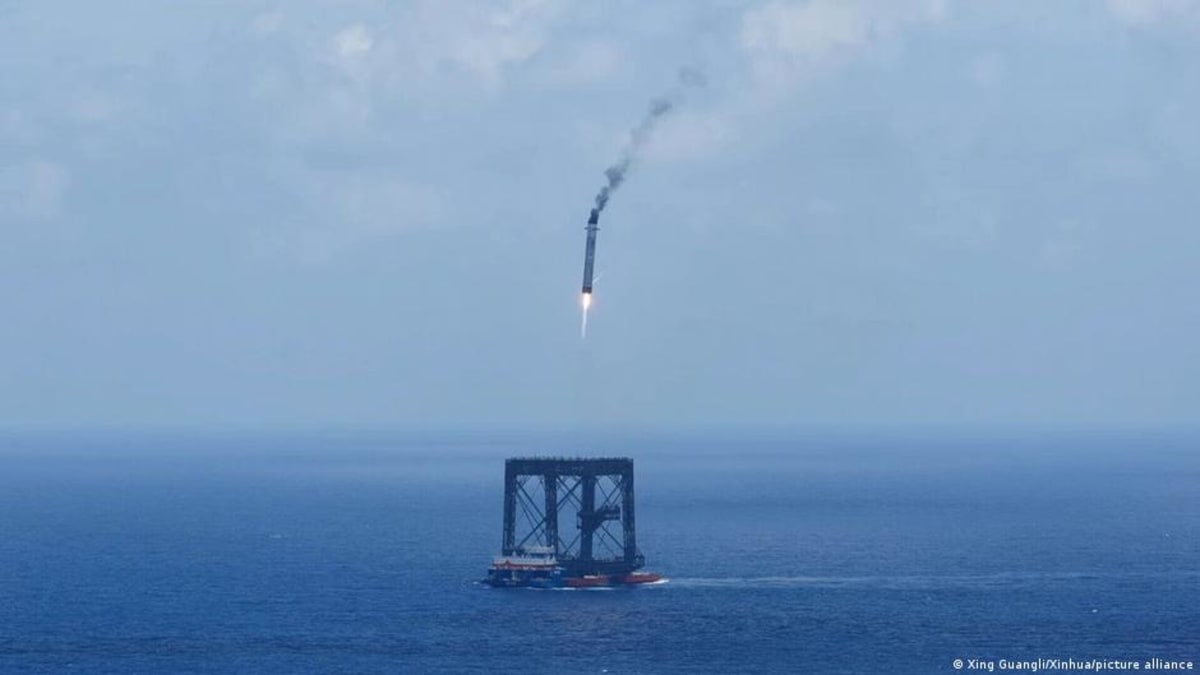 Long March 10B rocket booster descending vertically toward offshore platform with net capture system
